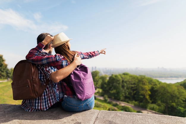 Una joven pareja está sentada en un parapeto.