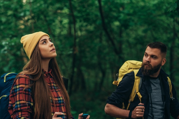 Una joven pareja de excursionistas usando bastones de trekking y usando mochilas