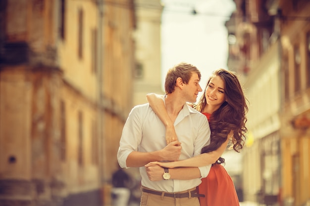 Joven pareja feliz abrazando en la calle de la ciudad.