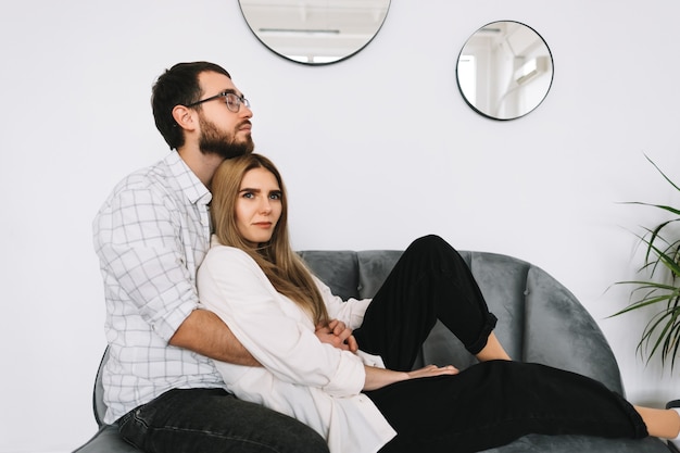 Joven pareja feliz abrazo y descansando en un sofá en casa.