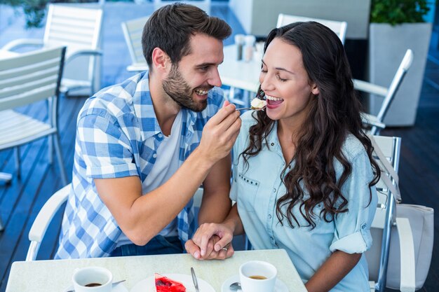 Joven pareja feliz alimentándose con pastel