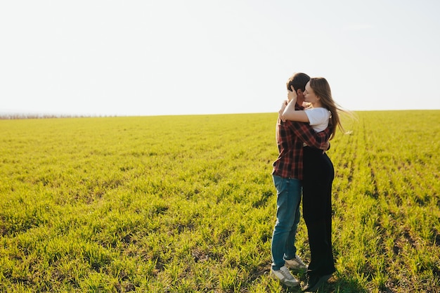 Joven pareja feliz en el amor abrazándose en un campo verde en un día soleado de primavera.