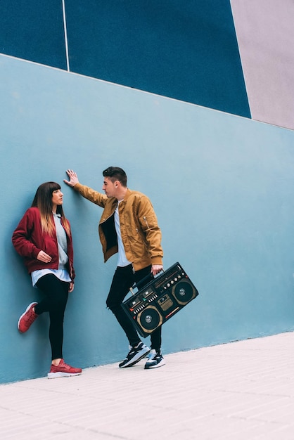 Joven pareja feliz bailando en la calle con un estéreo de radio casete vintage