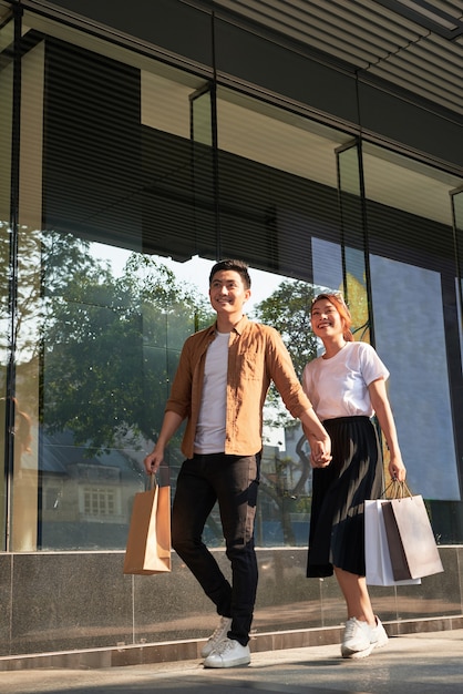 Joven pareja feliz con bolsas de compras en la ciudad.