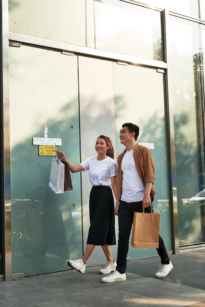 Joven pareja feliz con bolsas de compras en la ciudad.