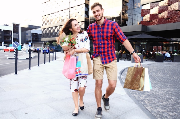 Joven pareja feliz con bolsas de compras en la ciudad.