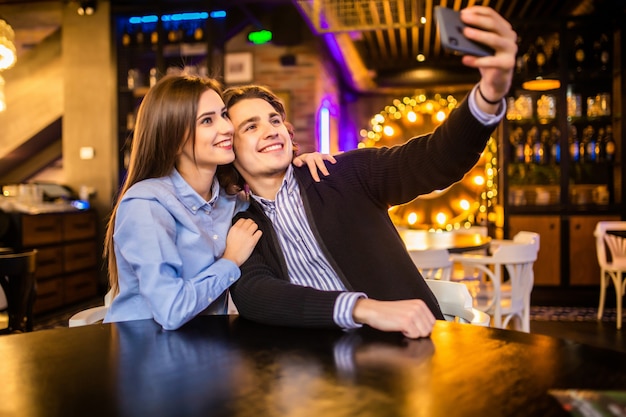 Joven pareja feliz en el café tomando selfie en café