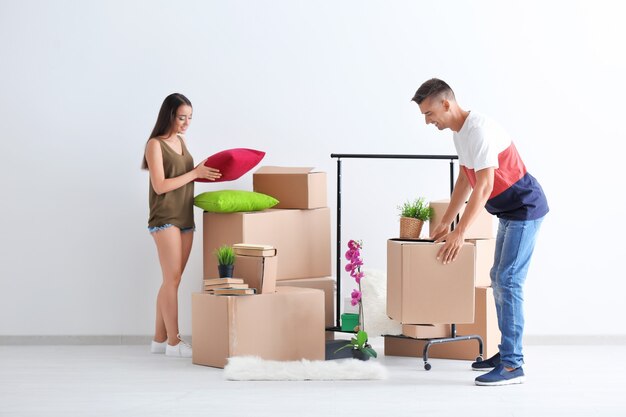 Joven pareja feliz con cajas de cartón en la habitación