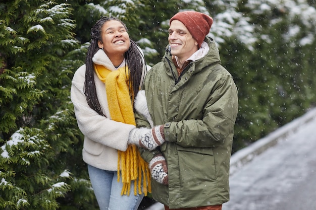 Joven pareja feliz caminando juntos en el bosque durante la nieve