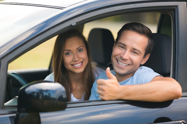 Joven pareja feliz en coche sonriendo - concepto de compra de coche