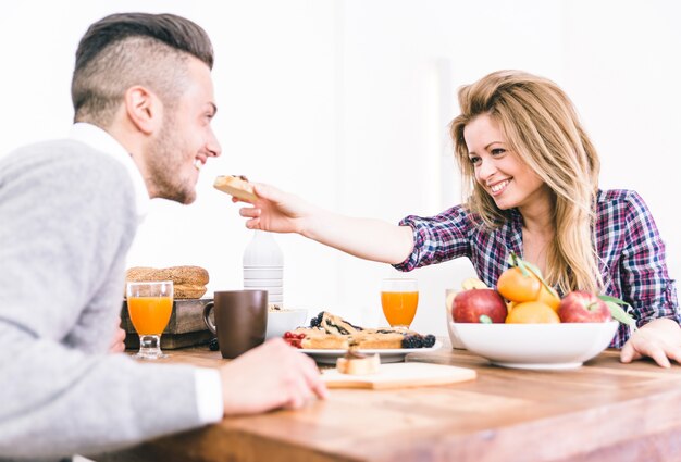 Joven pareja feliz desayunando en la mañana