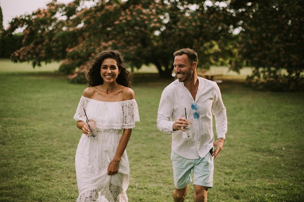 Una joven pareja feliz disfruta del hermoso entorno de un jardín con vasos de limonada fresca