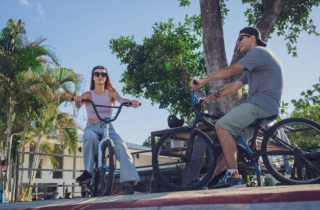 Una joven pareja feliz disfruta montando bmx en el skatepark