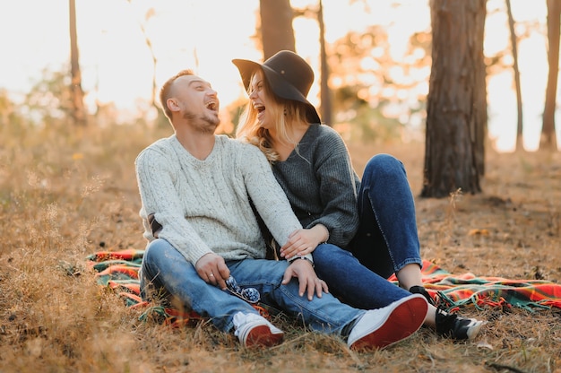 Joven pareja feliz divirtiéndose en el bosque al atardecer.