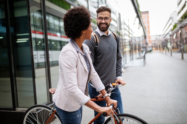 Joven pareja feliz divirtiéndose en la ciudad y andar en bicicleta