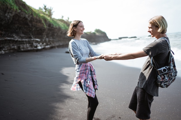 Joven pareja feliz divirtiéndose en la playa