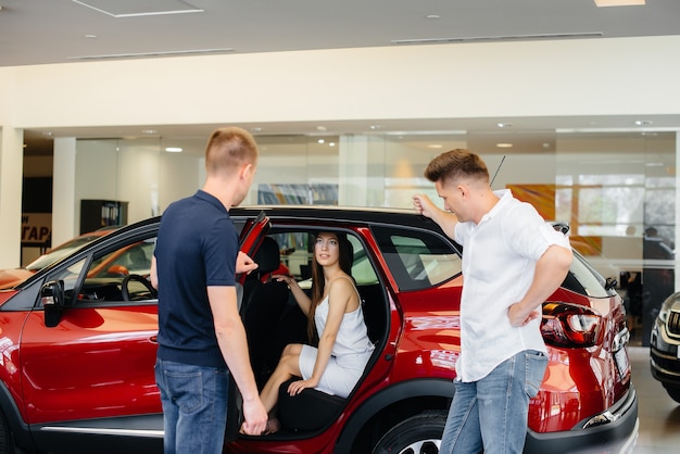 Una joven pareja feliz elige y compra un automóvil nuevo en un concesionario de automóviles