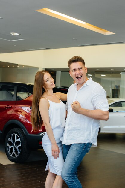 Una joven pareja feliz está feliz de comprar un coche nuevo