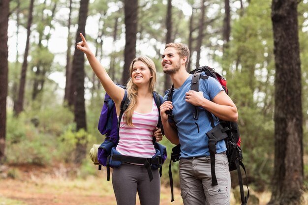 Joven pareja feliz excursionista apuntando en la distancia