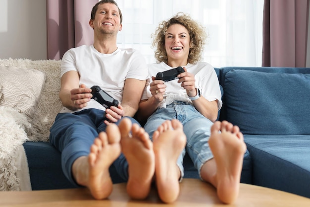 Foto joven pareja feliz con un gamepads está jugando la consola de videojuegos en casa