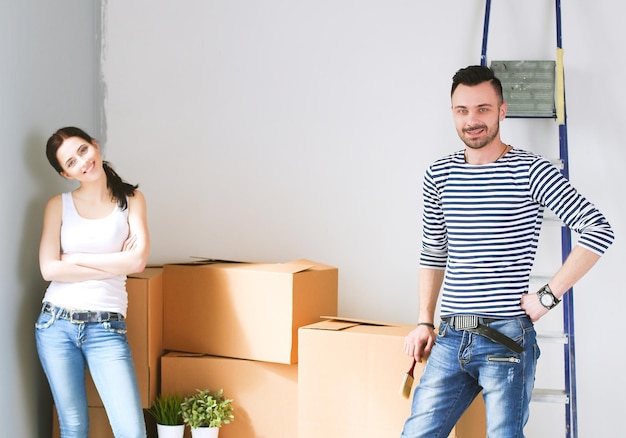 Joven pareja feliz en la habitación con cajas de mudanza en el nuevo hogar