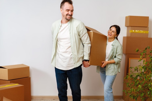 Joven pareja feliz en la habitación con cajas de mudanza en el nuevo hogar