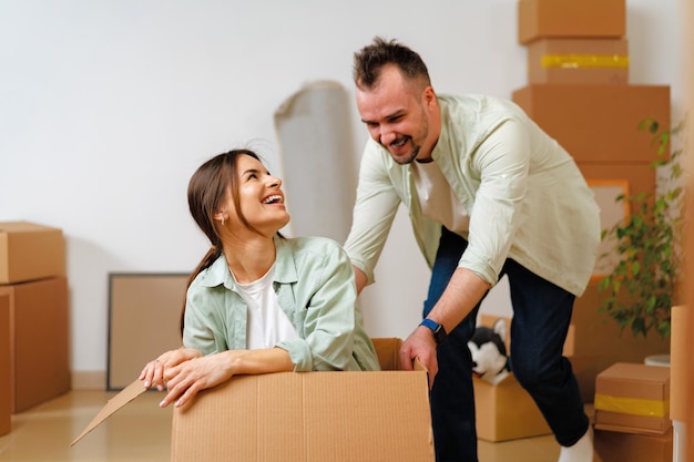 Joven pareja feliz en la habitación con cajas de mudanza en el nuevo hogar