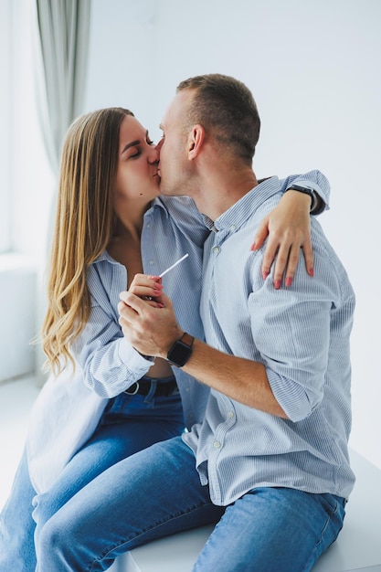 Una joven pareja feliz, un hombre y una mujer, recibieron una prueba de embarazo positiva y se regocijan.