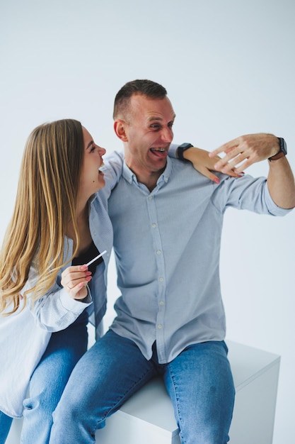 Una joven pareja feliz, un hombre y una mujer, recibieron una prueba de embarazo positiva y se regocijan.