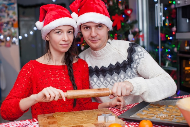 Joven pareja feliz hornear pasteles de Navidad