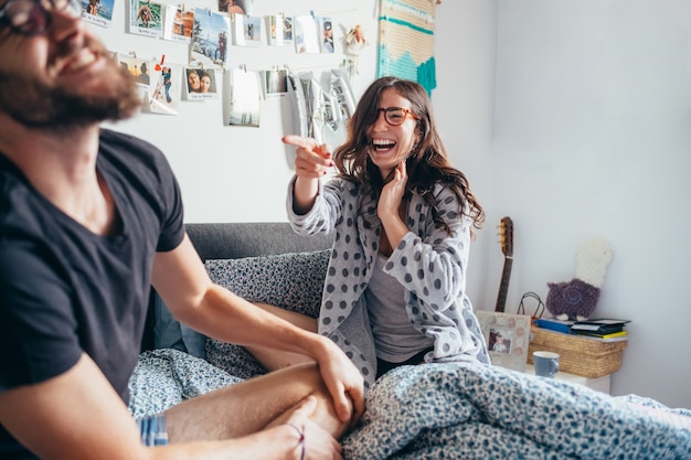 Joven pareja feliz jugando riendo en la cama interior casa riendo