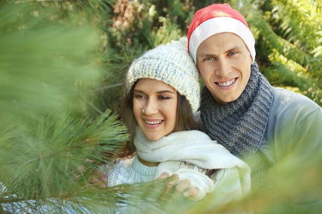 Joven pareja feliz en el mercado de árboles de Navidad