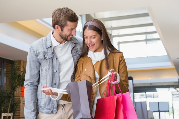 Joven pareja feliz mirando bolsas de compras