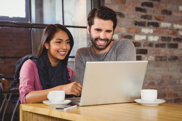 Joven pareja feliz mirando una computadora portátil