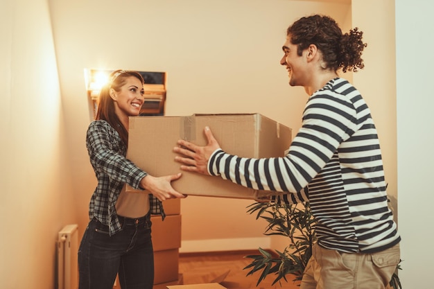 La joven pareja feliz se muda a una nueva casa. Traen cajas con cosas a su nuevo hogar.