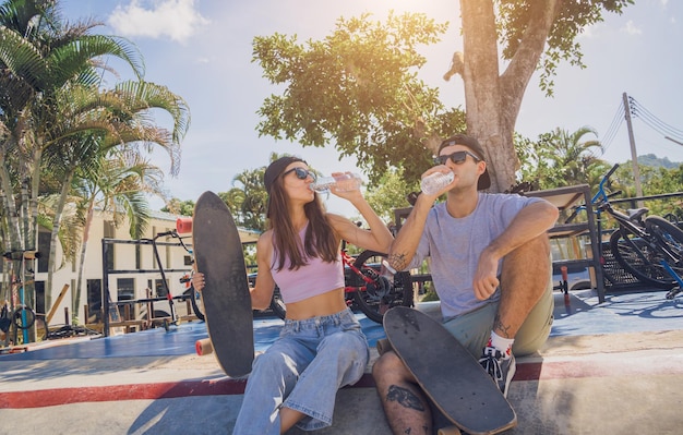 Foto una joven pareja feliz con patinetas disfruta del longboard en el skatepark