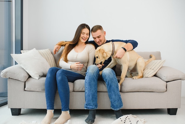Foto joven pareja feliz con perro sentado en el sofá