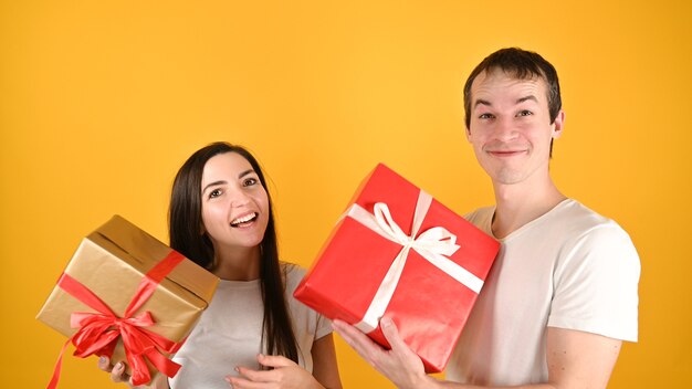 Joven pareja feliz recibió regalos el uno del otro en amarillo