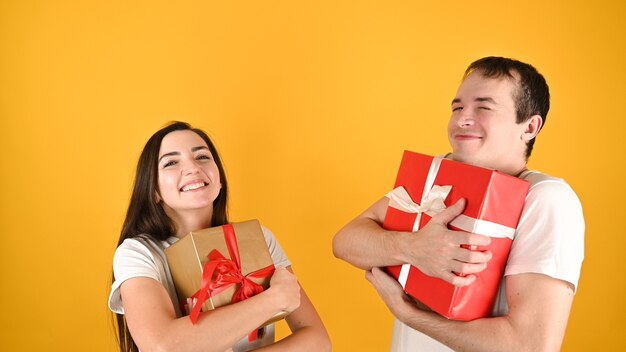 Foto joven pareja feliz recibió regalos el uno del otro en amarillo