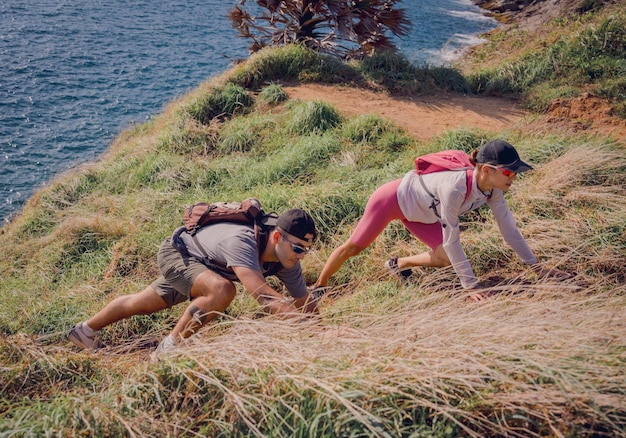 Una joven pareja feliz sube a la cima de las montañas cerca del océano.