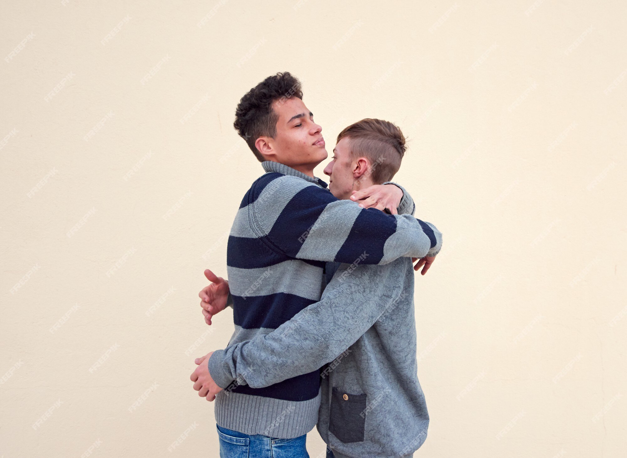 Una joven pareja gay interracial abrazos aislado sobre un fondo beige | Foto Premium Una joven pareja gay interracial abrazos aislado sobre un fondo beige | Foto Premium