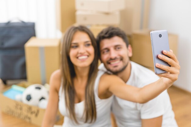 La joven pareja hace una foto en el fondo de las cajas de cartón.