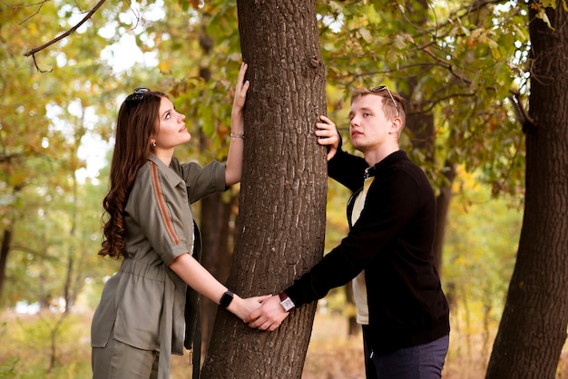 Una joven pareja hag el árbol en el bosque, conexión de personas con el concepto de naturaleza