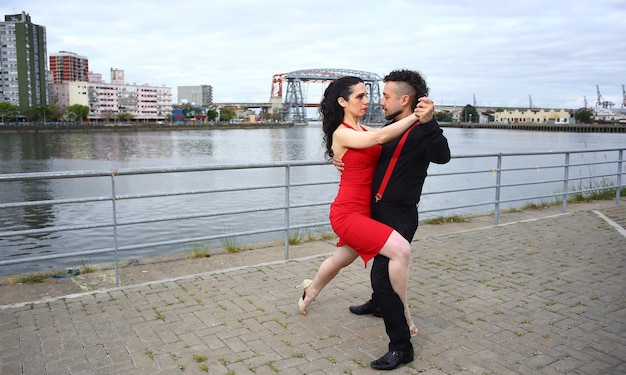 Foto joven pareja hermosa y profesional bailando tango en el muelle del río