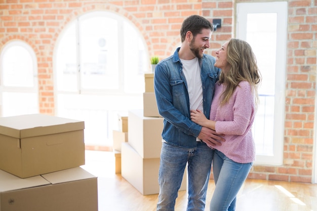 Joven pareja hermosa que se ve feliz juntos mudándose a un nuevo hogar