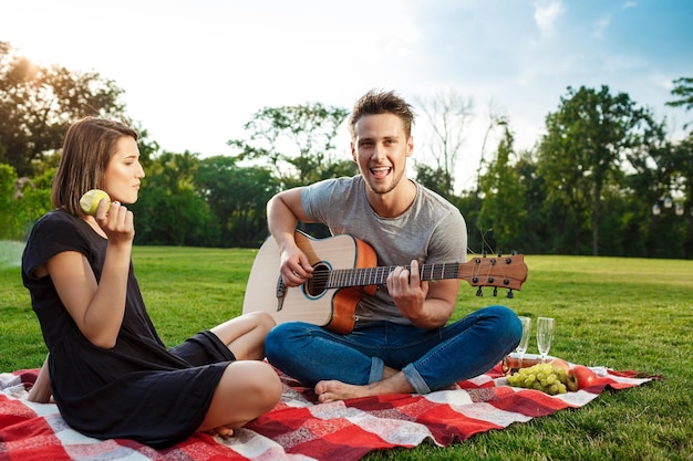 Joven pareja hermosa sonriendo descansando en un picnic en el parque