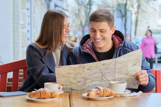 Joven pareja hermosa de turistas descansando en un café al aire libre