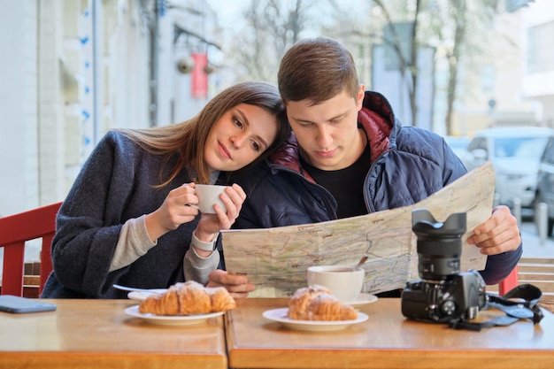 Joven pareja hermosa de turistas descansando en un café al aire libre