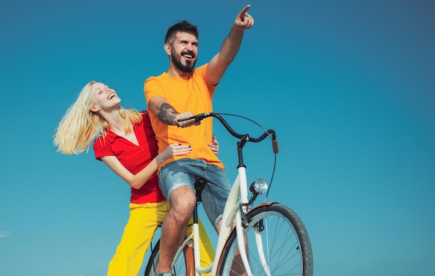 Joven pareja hippie sobre fondo azul cielo hermosa niña sonriente y hombre hipster barbudo está montando