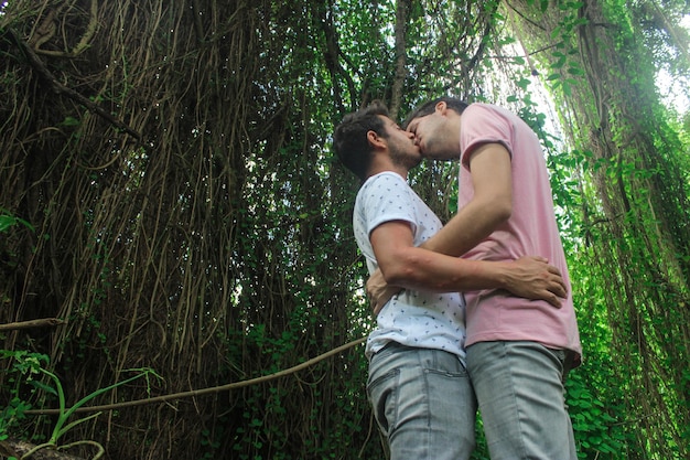 Una joven pareja de hombres gay besándose en el parque